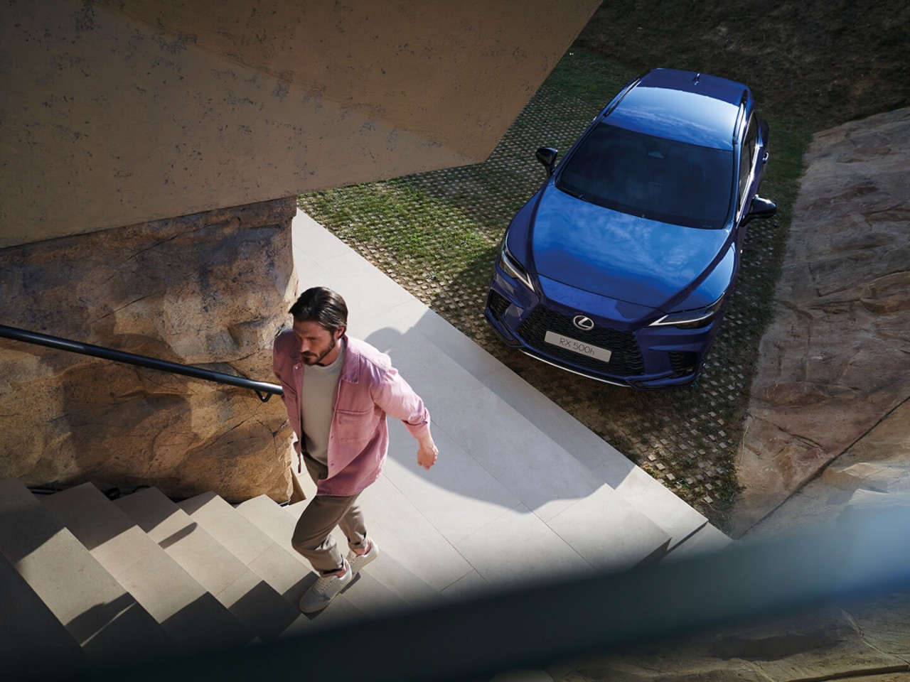 A man walking up stairs away from a parked Lexus RX 500h